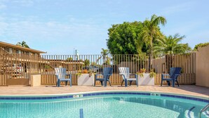 A swimming pool with clear blue water, surrounded by a tiled deck. There are four blue lounge chairs aligned along the pool's edge. - Hotel 414 Anaheim, Luxurious King Size Bed (Anaheim)