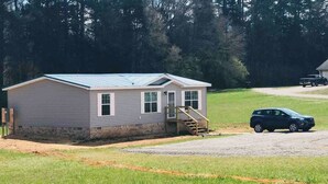 A single-story mobile home with a metal roof, a front porch, and a driveway. - The Hollywood (Hollywood)