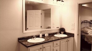 A bathroom with a double sink, a large mirror, and a vanity with cabinets. - The Hollywood (Hollywood)