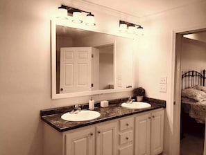 A bathroom with a double sink, a large mirror, and a vanity with cabinets.