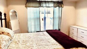 Ein Schlafzimmer mit einem Bett, einem Schminktisch, einem Spiegel und einem Fenster mit Vorhängen.
