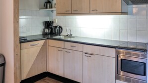 Une cuisine moderne avec des meubles de couleur bois clair, une hotte de cuisine en acier inoxydable et un four encastré.