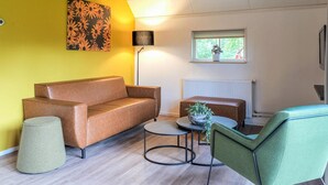 Un salon moderne avec un canapé en cuir marron, un fauteuil vert, une petite table ronde et un lampadaire.