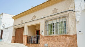 A building with a stone facade, a large garage door, and a window with decorative bars. - 5 bedroom beautiful home in Algamitas (Algamitas)