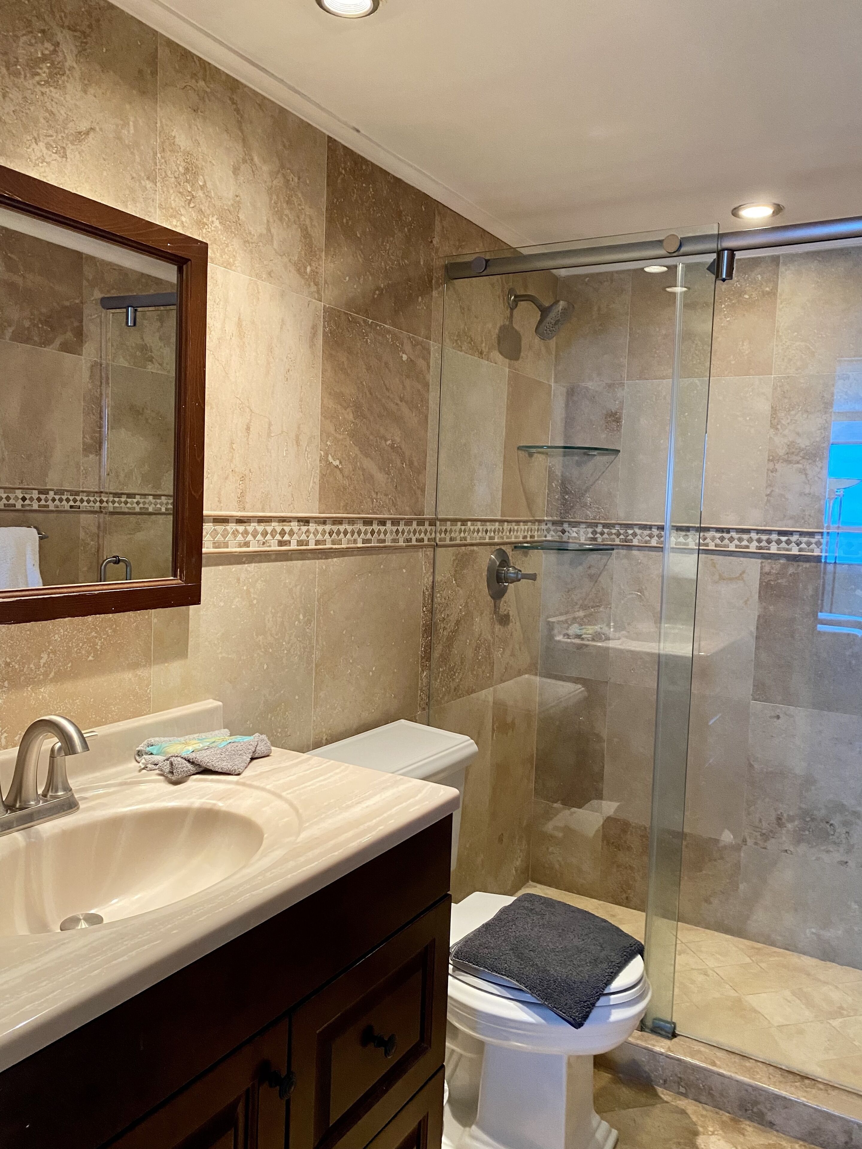 Un baño con cabina de ducha de vidrio, lavamanos y retrete.