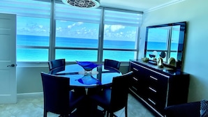 Un comedor con vista al océano, un ventilador de techo y un ventanal grande.