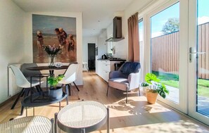 A modern living space with a dining area, kitchen, and a large sliding glass door leading to a garden. - Nice home in Heinkenszand with kitchen (Heinkenszand)