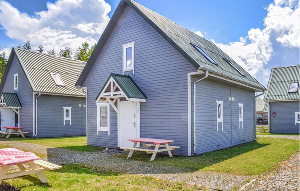 A row of blue cabins with pitched roofs and white trim, each with a small porch and a picnic table. - Awesome home in Rewal with WiFi (Rewal)
