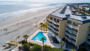A hotel with a rooftop pool, beachfront view, and multiple balconies.