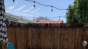 Ein Patio-Bereich mit Feuerstelle, zwei türkisfarbenen Adirondack-Stühlen und einem Holzzaun.