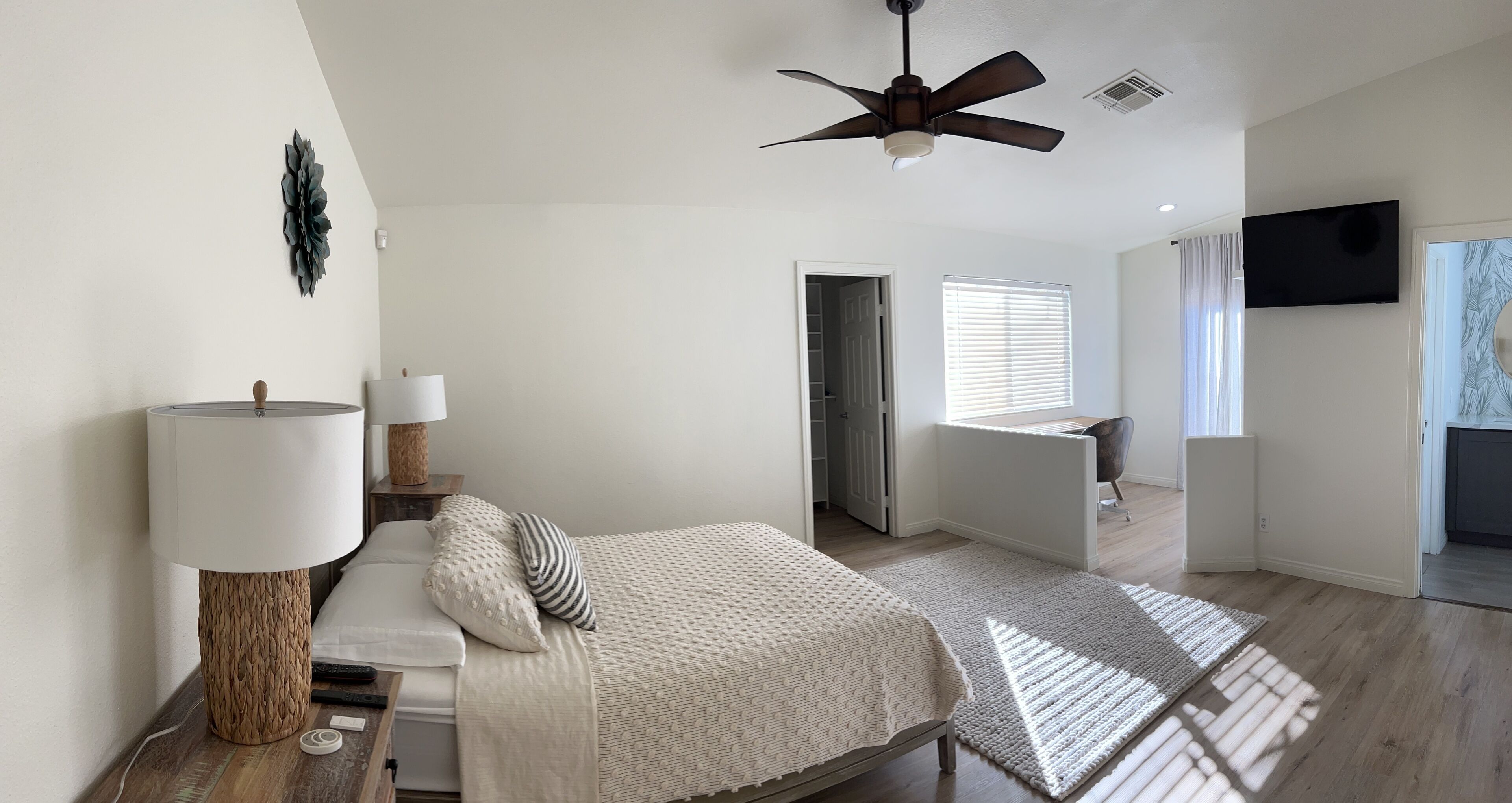 Un dormitorio con cama, lámpara de noche y ventilador de techo.
