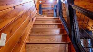 Eine Holztreppe mit Metallgeländer, die zu einer oberen Etage führt.