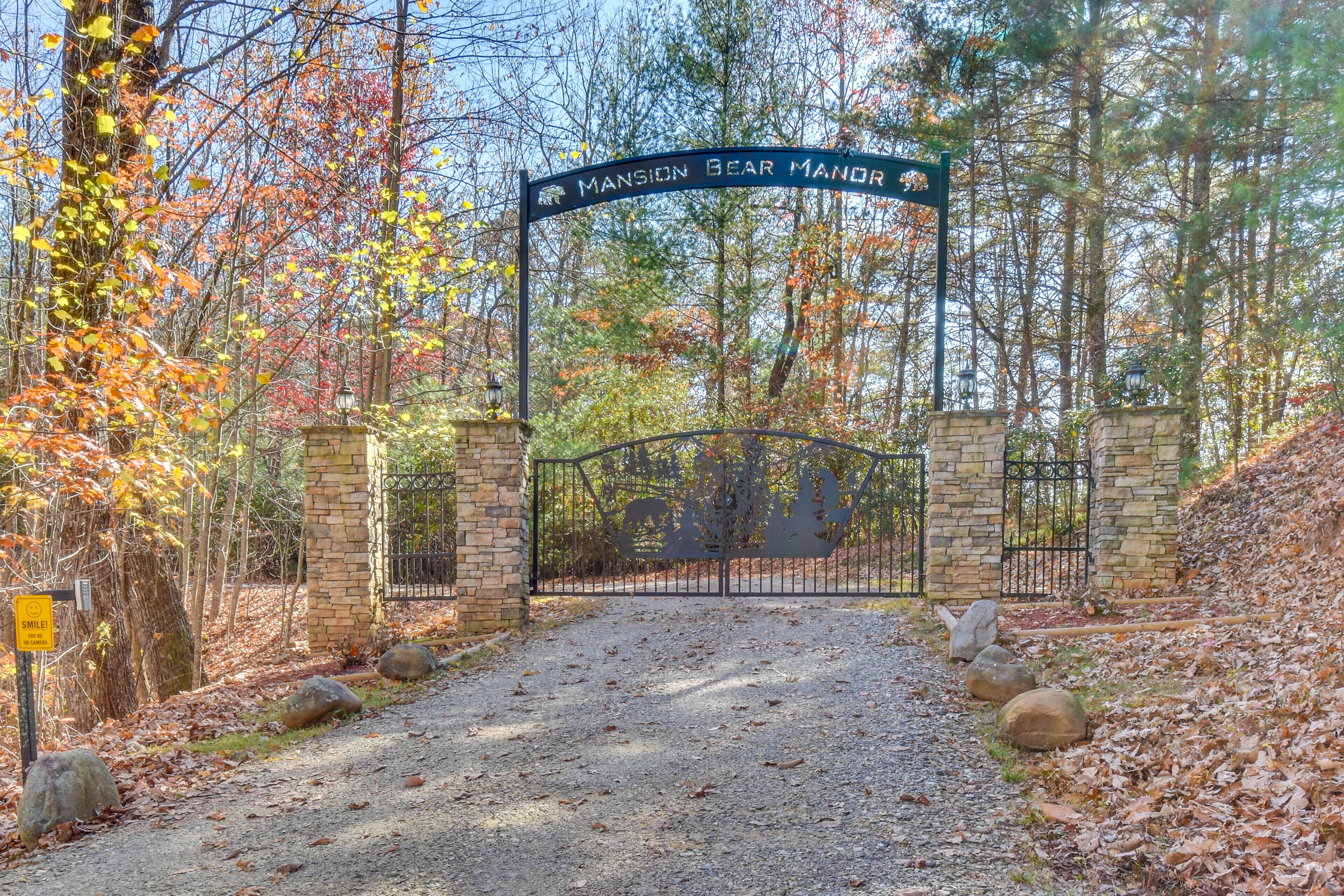 Une entrée fermée par un portail mène à une propriété appelée « Mansion Bear Manor », et un chemin de gravier traverse une zone boisée.