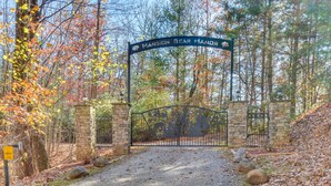 A gated entrance to a property named "Mansion Bear Manor" with a gravel path leading through a wooded area. - Hot Tub, Arcade & Casino! Blue Ridge Mtn Mansion (Blairsville)