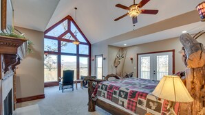 A spacious bedroom with a large bed, a ceiling fan, and a view of the outdoors. - Hot Tub, Arcade & Casino! Blue Ridge Mtn Mansion (Blairsville)