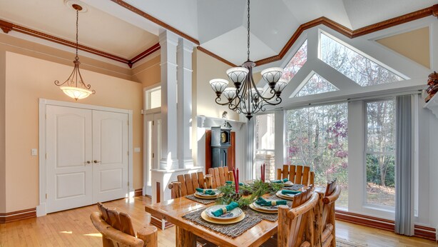 A dining area with a wooden table set for six, surrounded by wooden chairs. - Hot Tub, Arcade & Casino! Blue Ridge Mtn Mansion (Blairsville)