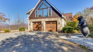 A two-story house with a stone facade, a gabled roof, and a garage with wooden doors. - Hot Tub, Arcade & Casino! Blue Ridge Mtn Mansion (Blairsville)