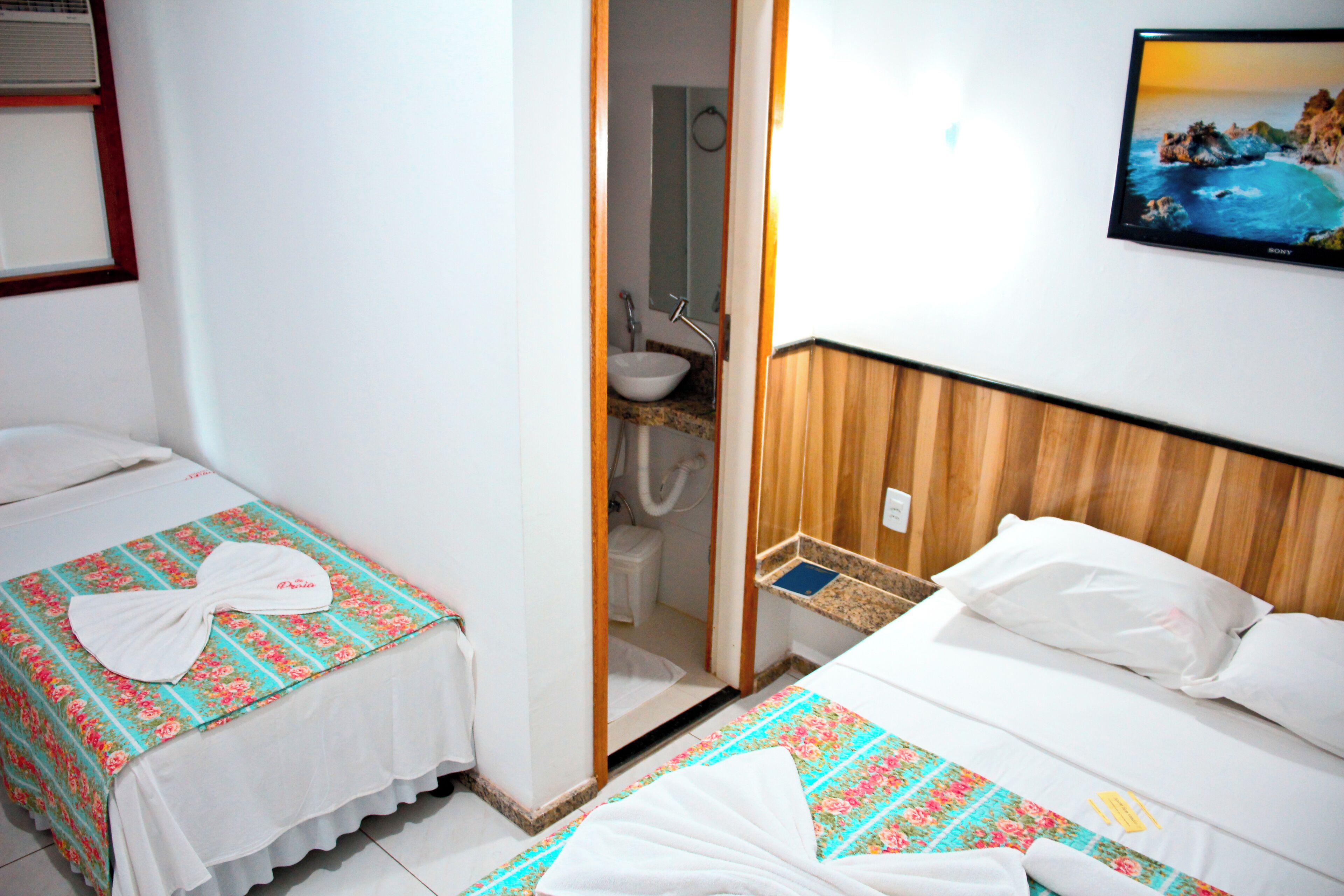Habitación de hotel con dos camas, un baño y un cuadro en la pared.