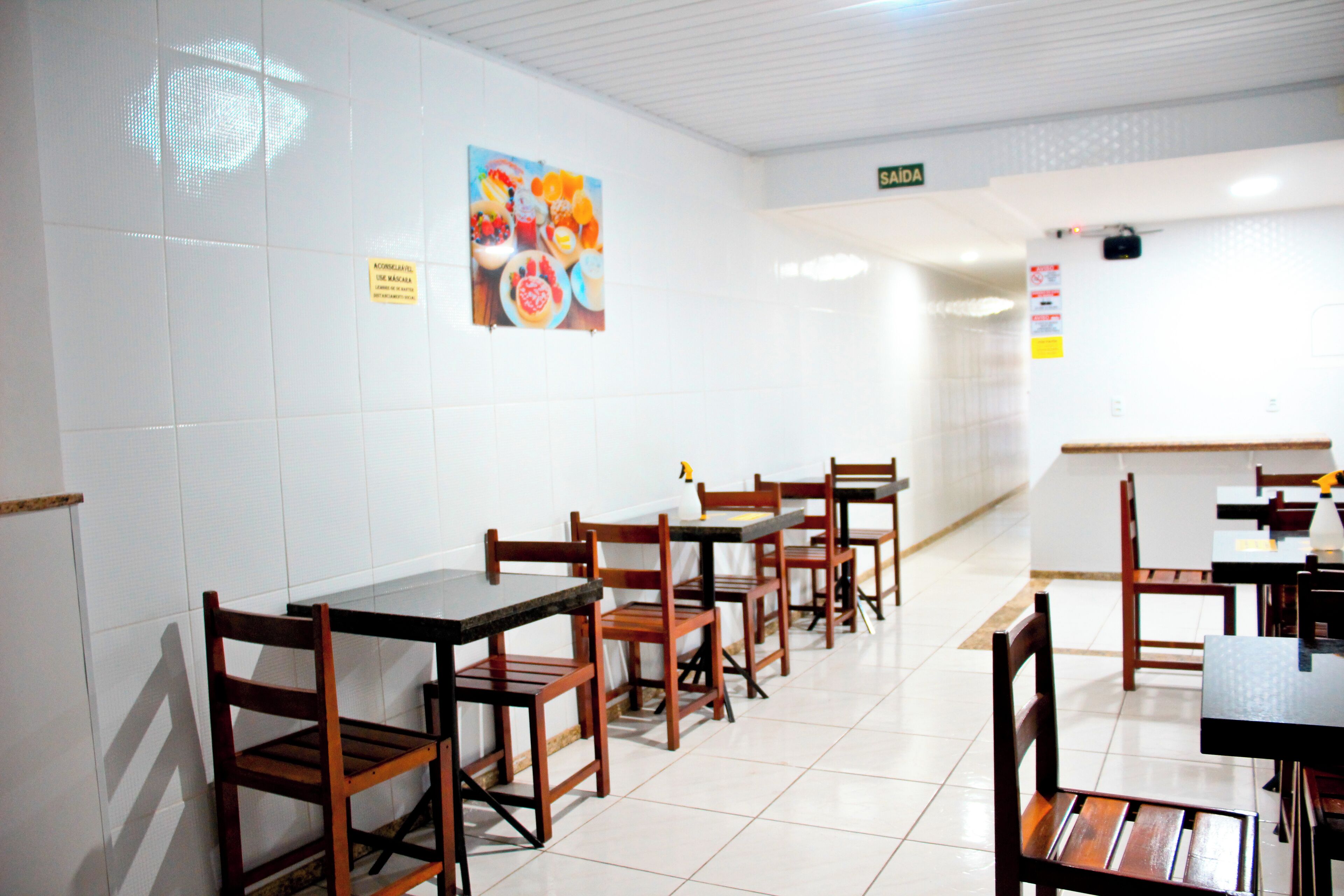 A restaurant with wooden tables and chairs, tiled floors, and a wall with a fruit display.