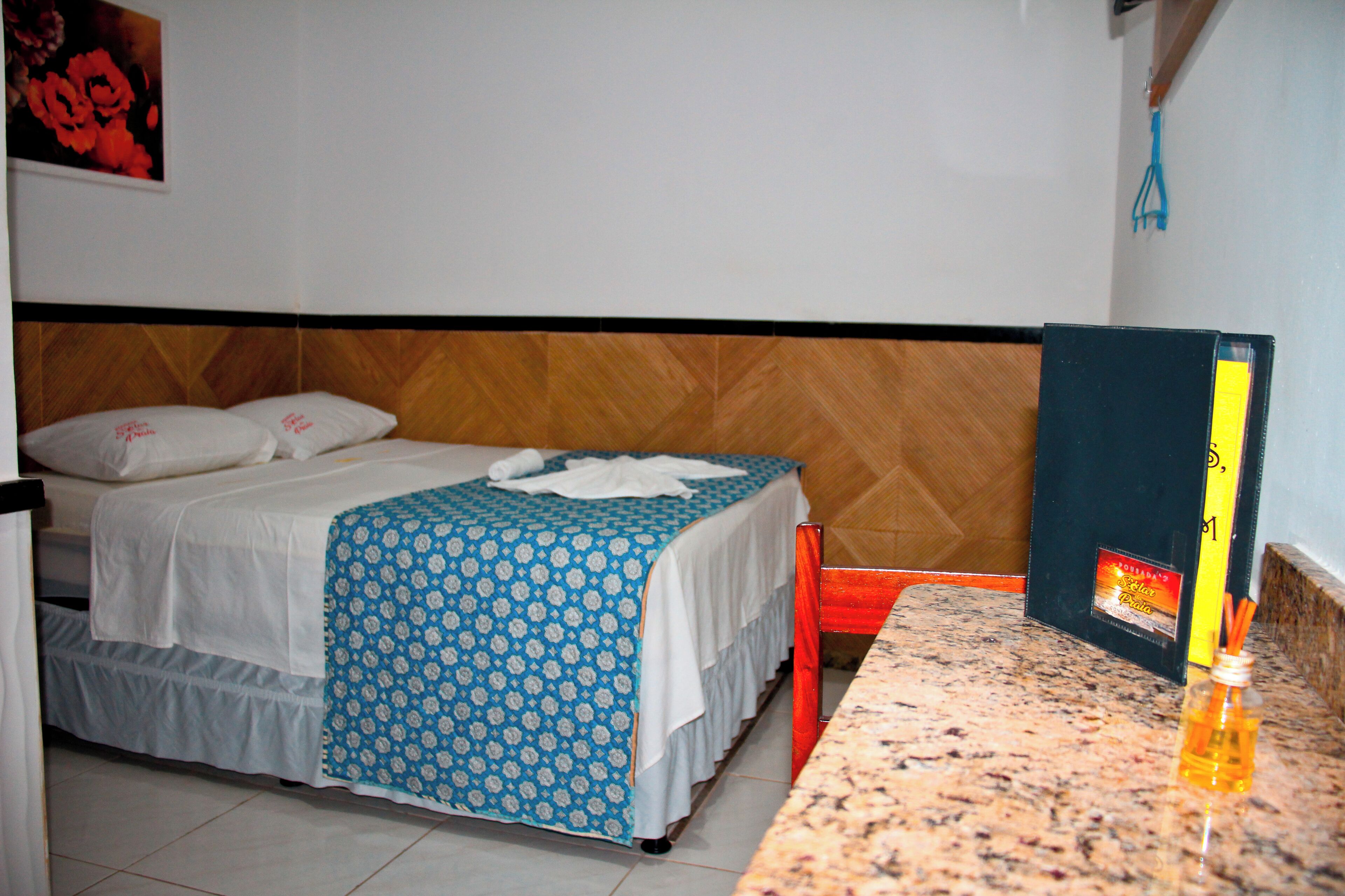 Een hotelkamer met een bed, een houten hoofdbord, een klein tafeltje en een nachtkastje.