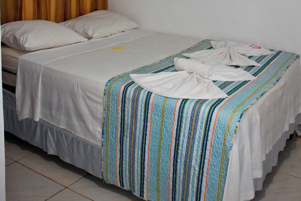 A single bed with a striped blanket, a wooden headboard, and a framed picture on the wall.