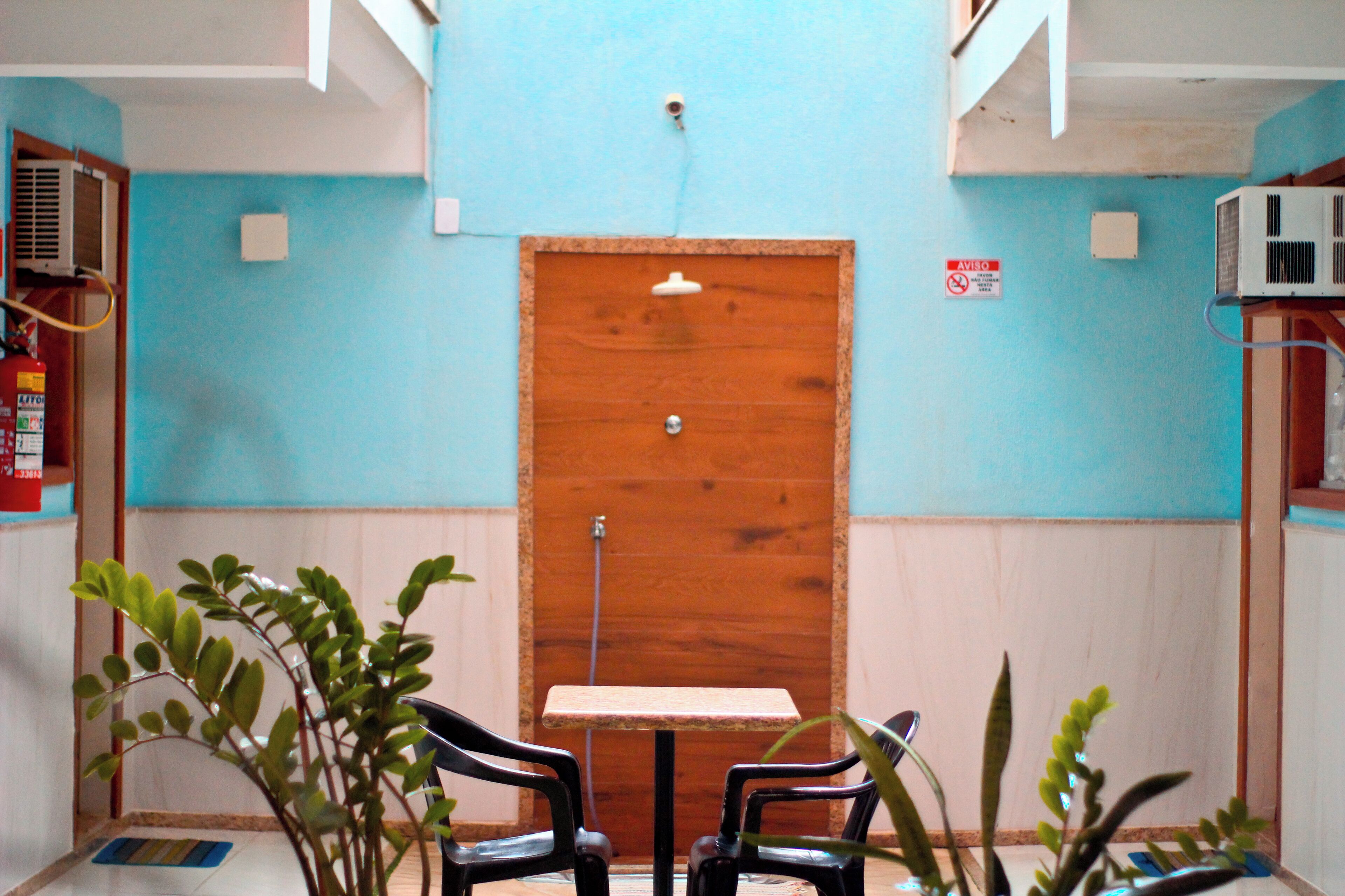 A room with a wooden door, a small table, two chairs, and a potted plant.