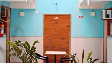 A room with a wooden door, a small table, two chairs, and a potted plant.
