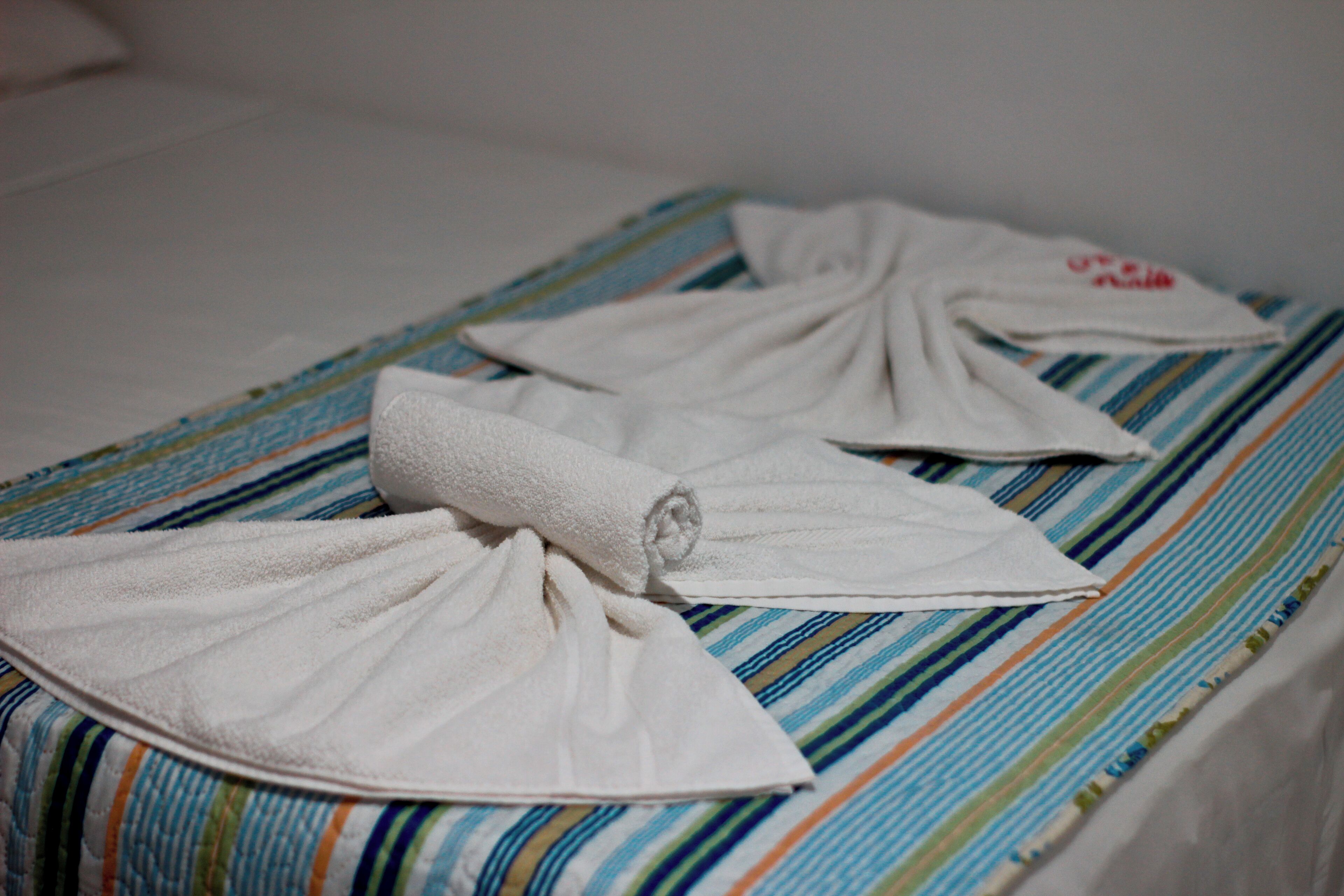 Uma cama com colcha listrada e duas toalhas brancas dobradas.