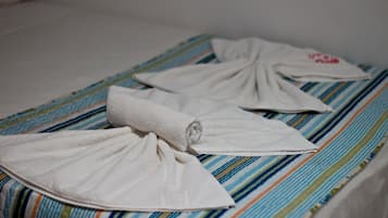 Uma cama com colcha listrada e duas toalhas brancas dobradas.
