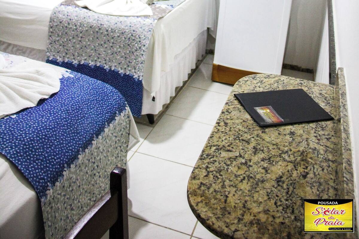 A hotel room with two beds, a small kitchenette, and a television.