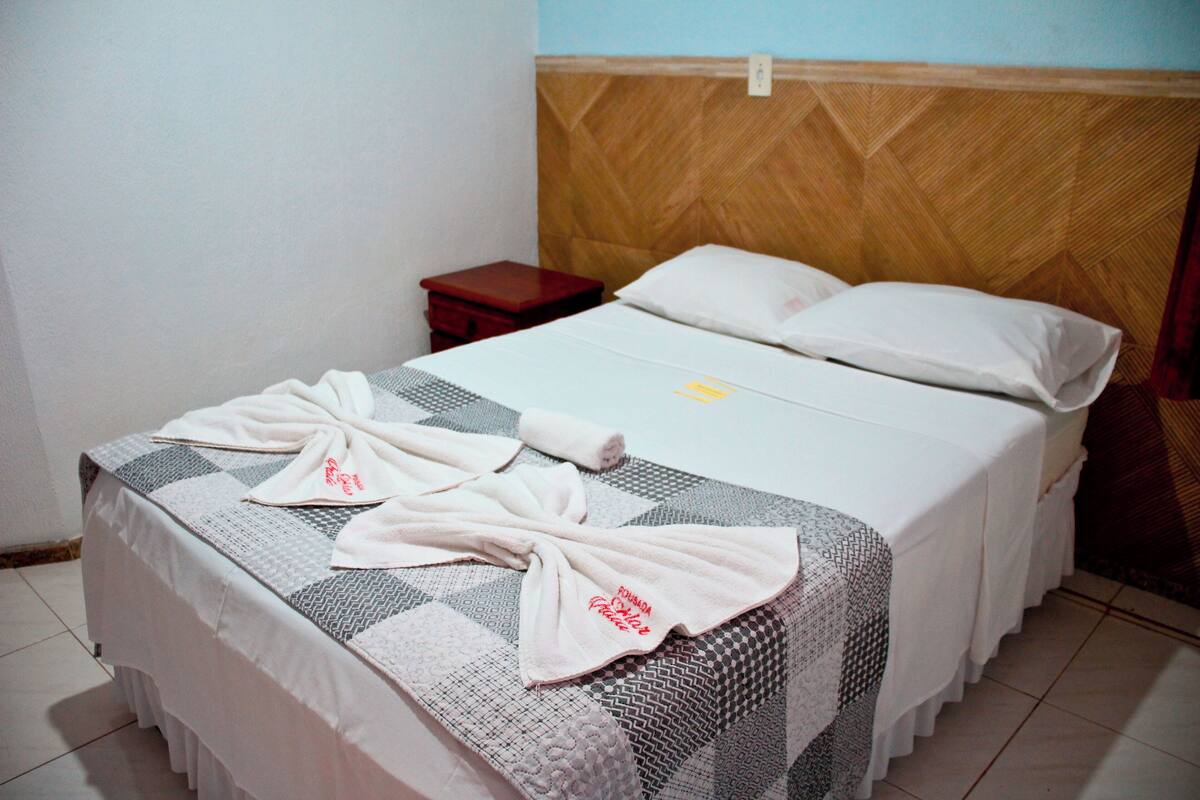 A neatly made bed with a checkered bedspread and two towels folded on top.