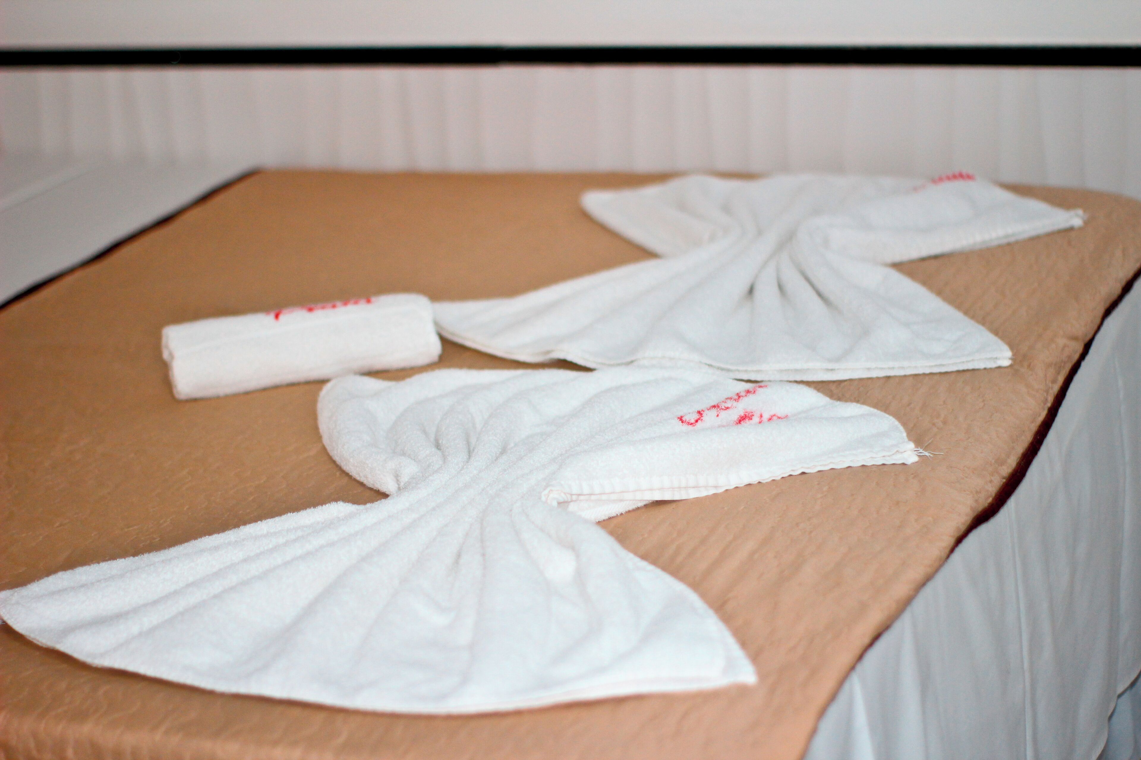 Un ensemble de serviettes blanches, soigneusement disposées sur un plateau en bois, dans une chambre d’hôtel.
