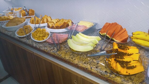 Un buffet proposant une variété de plats, notamment des fruits, des pâtisseries et d’autres mets.