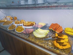 Un bufé con diferentes opciones de comida, incluyendo frutas, pasteles y otros platos.