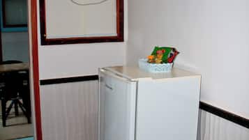 Una habitación pequeña con un refrigerador blanco, una mesita y una silla.