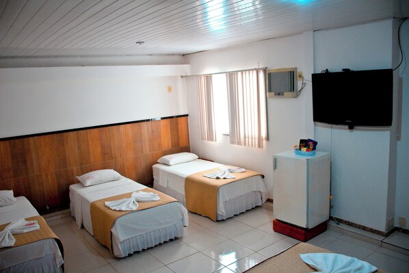 A hotel room with two beds, a TV, and a small refrigerator.