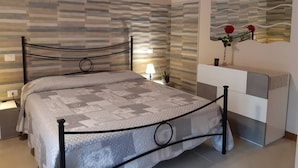 A bedroom with a bed, a bedside table, a lamp, a dresser, and a mirror. - Alghero Rural Relax & Private Comfort Exclusive Villa Laurus (Alghero)