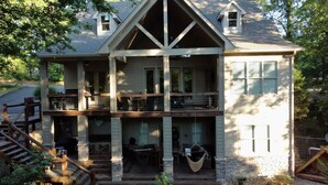 A two-story house with a balcony, a stone staircase, and outdoor seating. - Castaway Cove-Hot Tub, Boat Dock + Theater Room (Hot Springs)