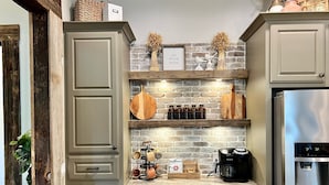 A kitchen with a brick wall, wooden shelves, a stainless steel refrigerator, and a coffee maker. - Castaway Cove-Hot Tub, Boat Dock + Theater Room (Hot Springs)