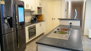 A modern kitchen with stainless steel appliances, a built-in microwave, and a sink. - FAMILY HOLIDAY HOME (Redbank Plains)