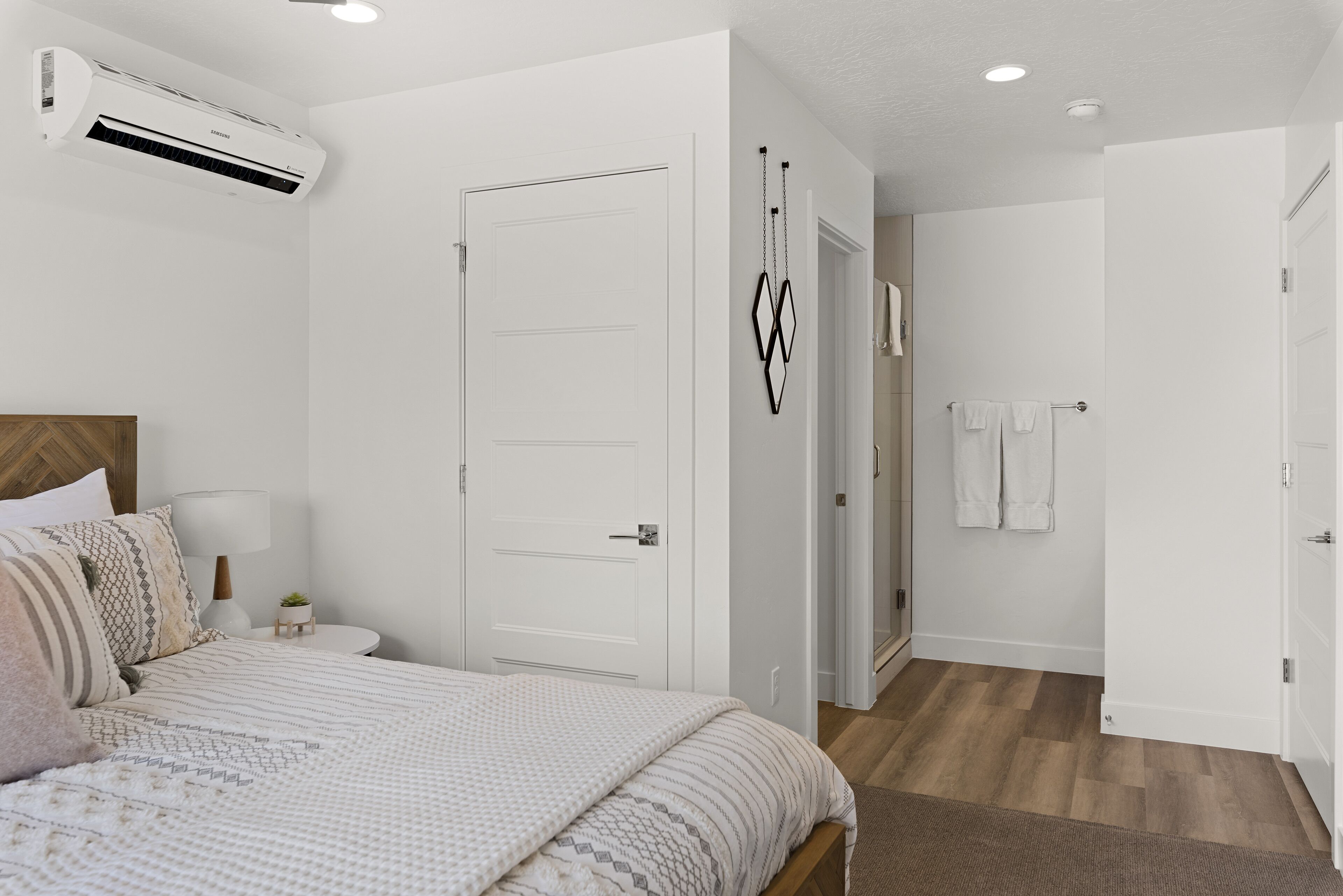 A bedroom with a bed, bedside table, lamp, and air conditioning unit.