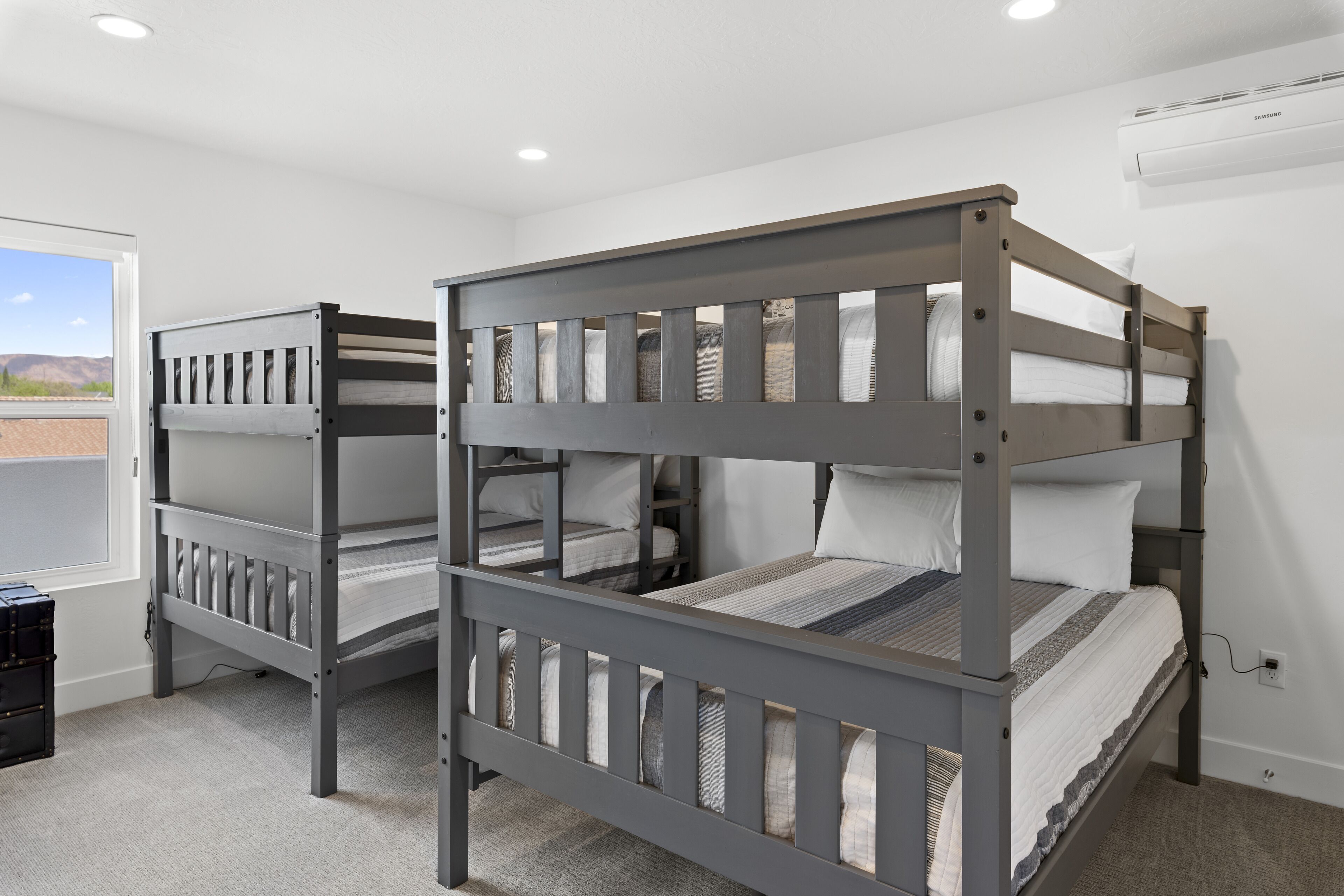 A bunk bed room with a window view, a ceiling fan, and a power outlet.