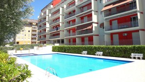 A multi-story hotel with balconies, a swimming pool, and a well-maintained garden. - Beautiful Beach Apartment With Shared Swimming Pool (Caorle)