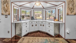 A corner kitchen with white cabinetry, a central island, and a view of the outdoors. - Silo House (Fairhope)