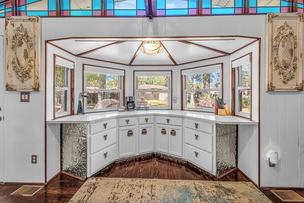A corner kitchen with white cabinetry, a central island, and a view of the outdoors.