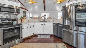 A kitchen with stainless steel appliances, wooden beams, and a ceiling fan. - Silo House (Fairhope)