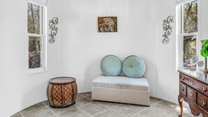 A room with a wooden ceiling, a chandelier, a bench with decorative pillows, a round table, and a dresser with drawers. - Silo House (Fairhope)