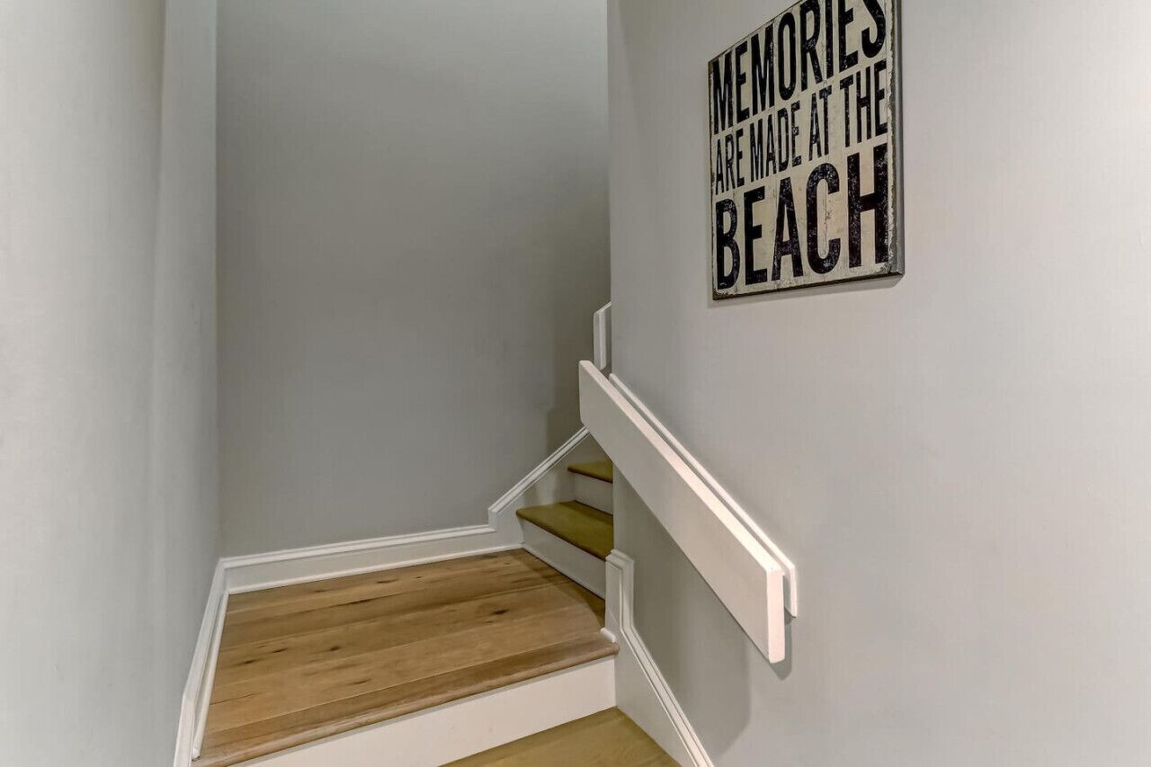 Un escalier avec des marches en bois et des rampes blanches, menant à un palier.
