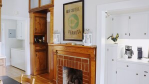 Une cuisine avec une cheminée en bois, une plaque décorative encadrée au-dessus du foyer et des armoires blanches.