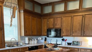 Une cuisine avec des meubles en bois, un îlot central, un four à micro-ondes et un grille-pain.